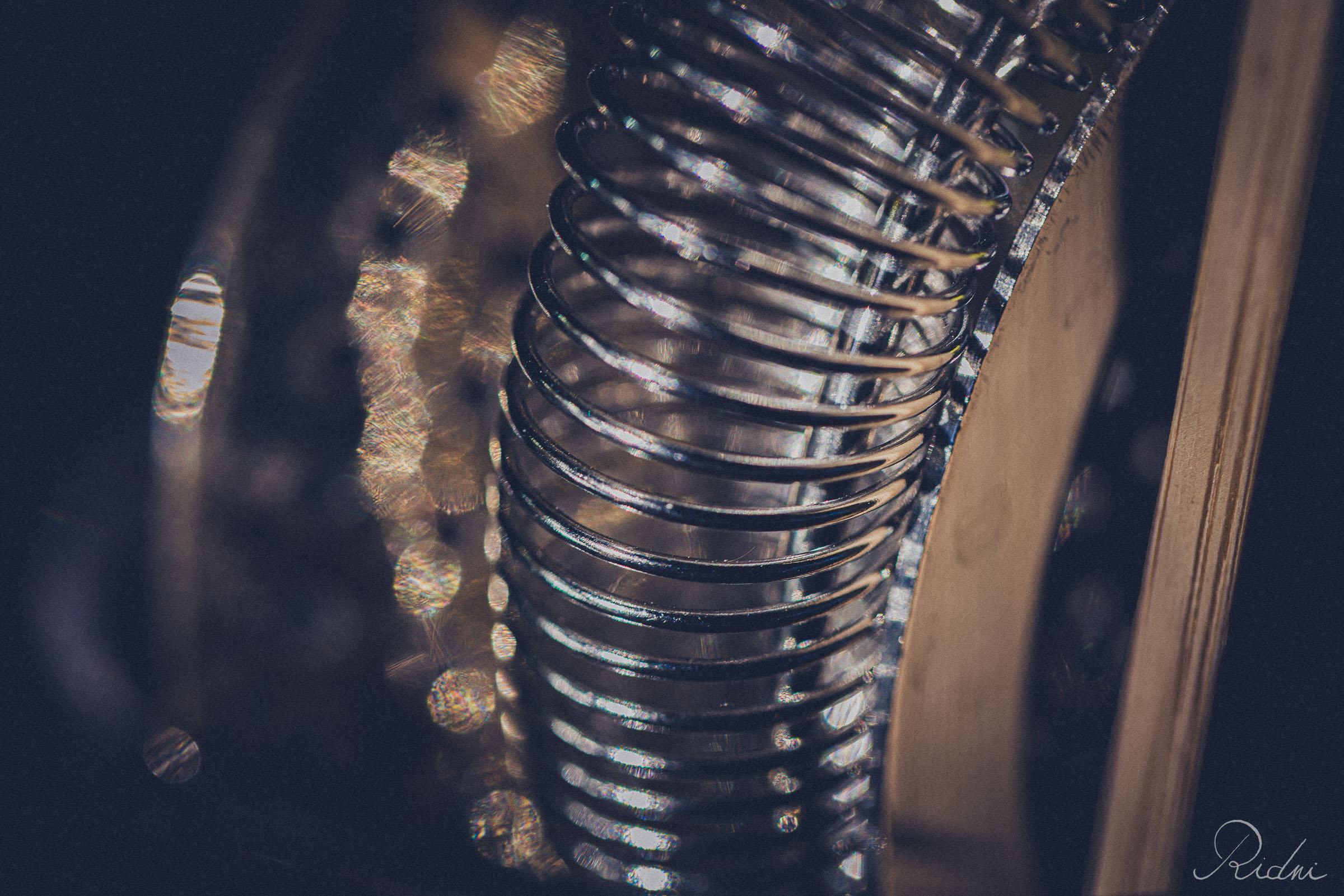 Macro view of a metallic spring from a cocktail strainer at bar Zona in lignano, friuli, reflecting soft ambient light.